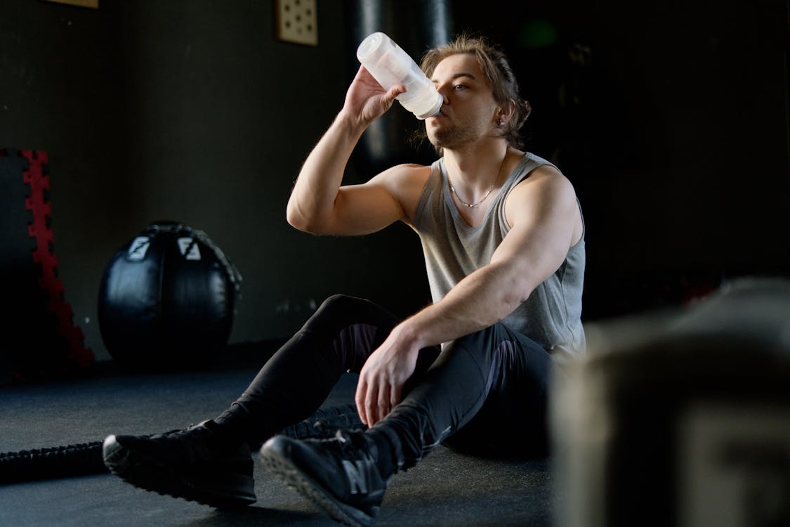 Free Man Sitting on the Floor and Drinking Water Stock Photo