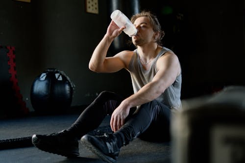 Man Sitting on the Floor and Drinking Water