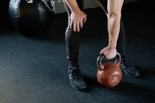 A person lifting a 32 kg kettlebell in a gym setting, focusing on strength and fitness.