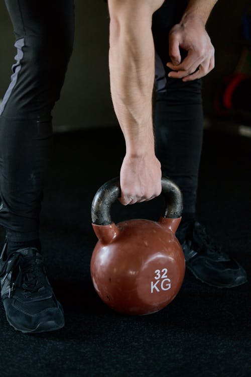 Free Person in Black Pants Holding Red Kettlebell Stock Photo