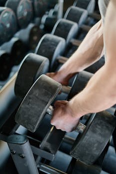Focused shot of hands holding large dumbbells in a gym setting, showcasing strength workout.