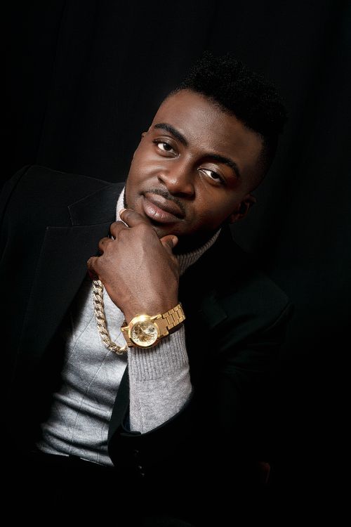Free Portrait of a stylish black man wearing a gold watch and chain, posing in a studio setting. Stock Photo