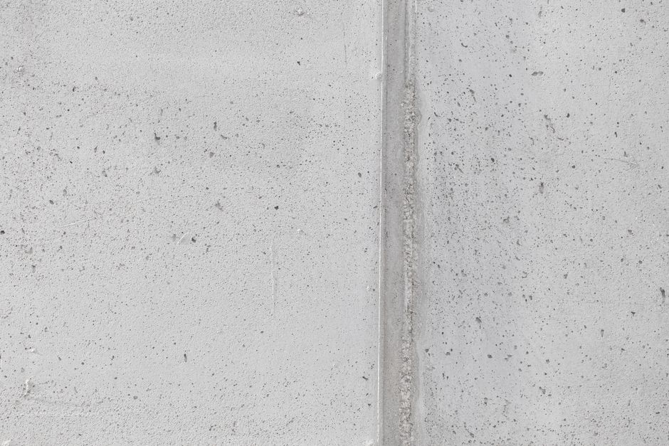 Close-up of a textured concrete wall with a vertical seam, perfect for backgrounds.