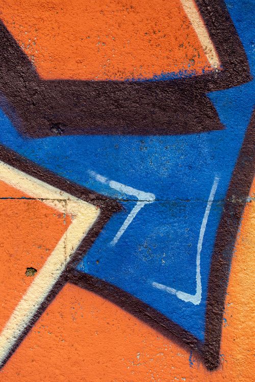 Free Close-up of colorful graffiti on a vibrant orange concrete wall with blue and black accents. Stock Photo