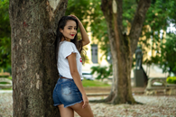 Back view of slim teenager with red lips wearing casual outfit standing in park