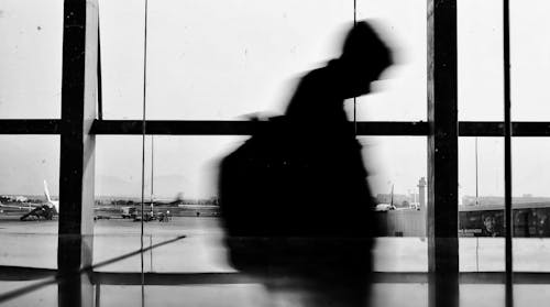 A Silhouette of a Person Walking in an Airport