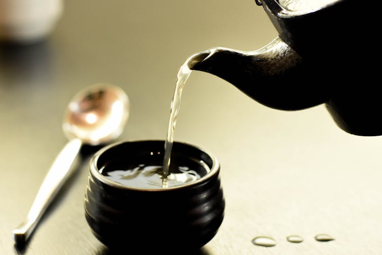 Person Pouring Water On Cup