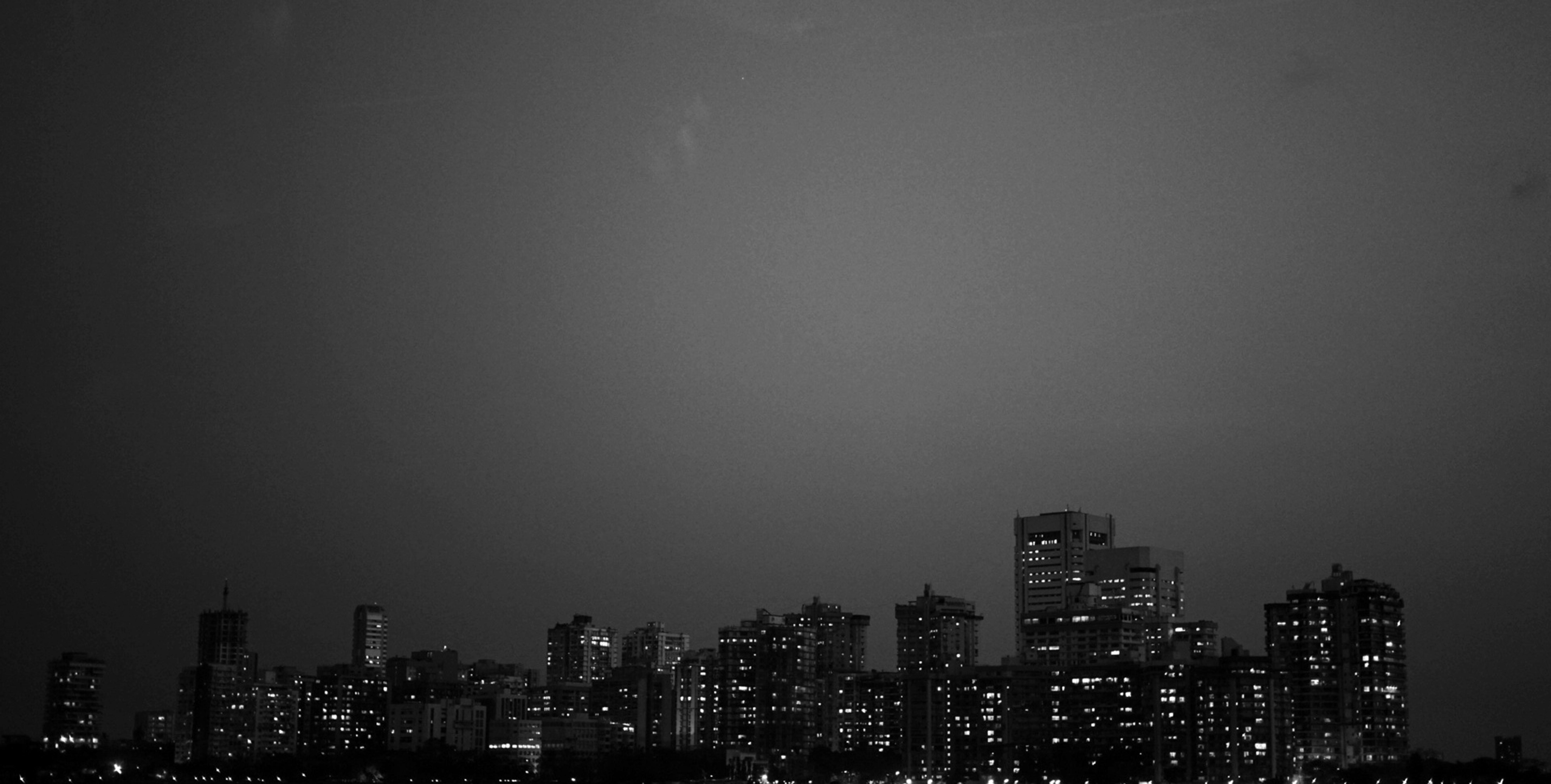 夜空中，明亮的摩天大楼勾勒出戏剧性的黑白城市景观