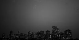 夜空中，明亮的摩天大楼勾勒出戏剧性的黑白城市景观