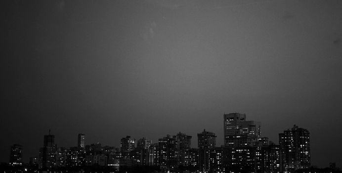 夜空中，明亮的摩天大楼勾勒出戏剧性的黑白城市景观