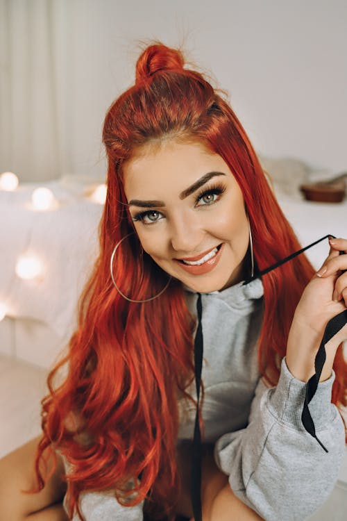 Cheerful cool woman with bright red hair looking at camera