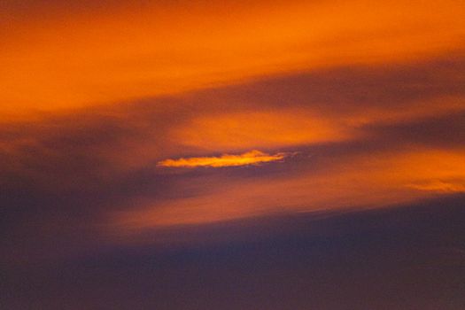 From below of spectacular view of thick clouds in bright orange sky at sundown at night