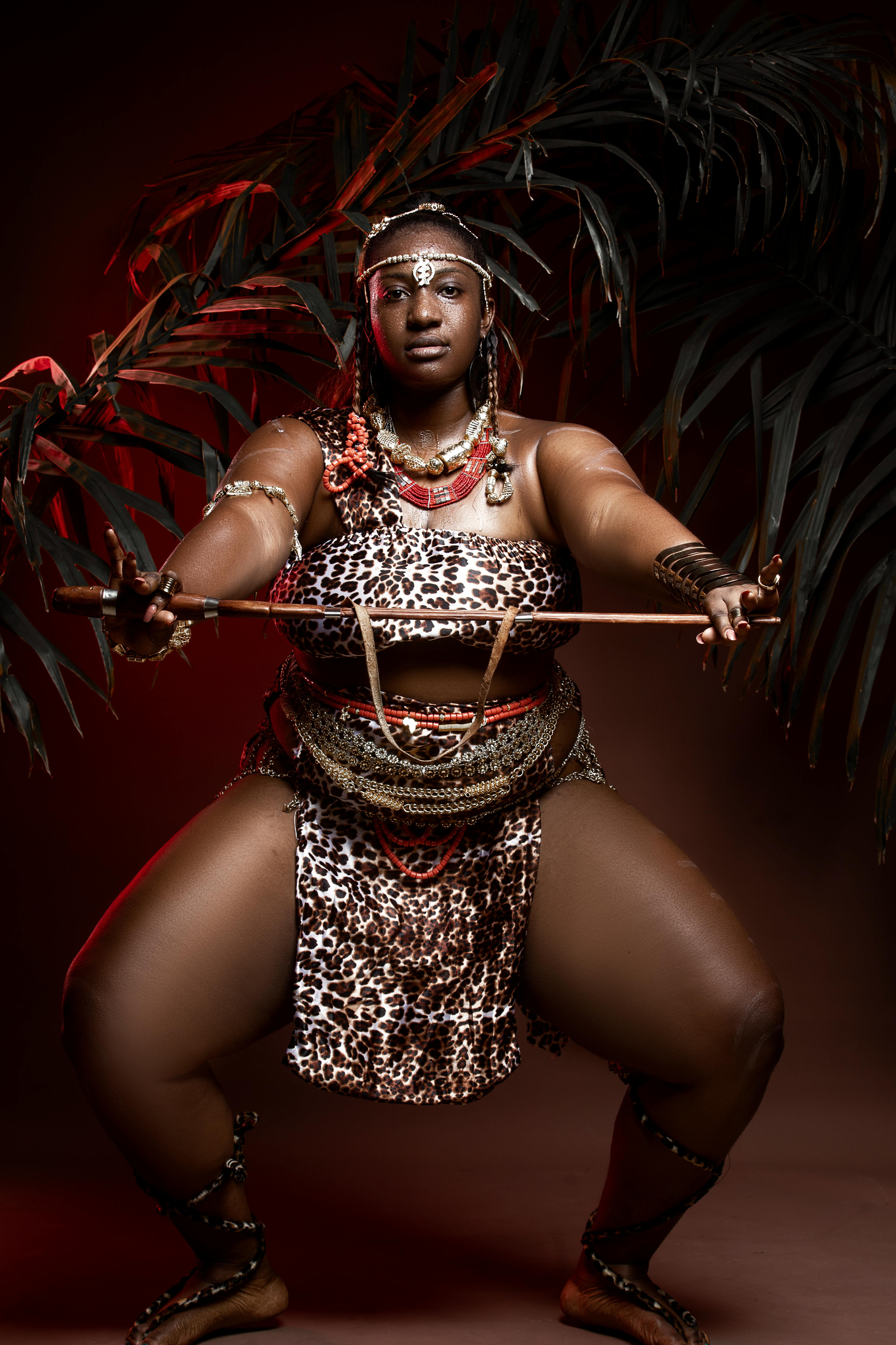 black female dancer squatting with wooden stick at night