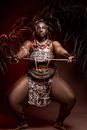 Black female dancer squatting with wooden stick at night