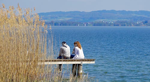 Man and Woman Sitting on Dock