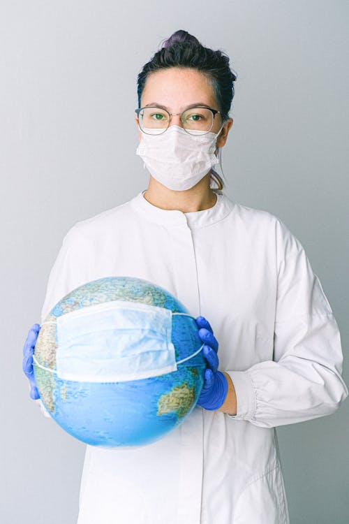 Free Photo Of Person Wearing Protective Wear While Holding Globe Stock Photo