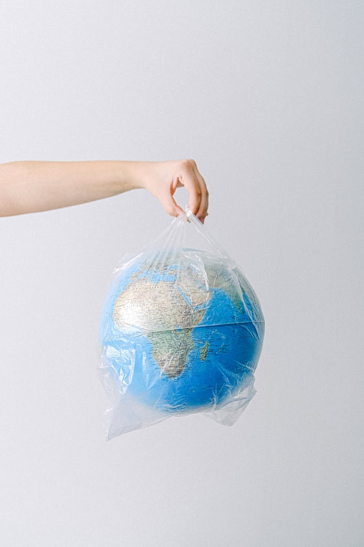 A Person Holding A Plastic Bag With A Globe