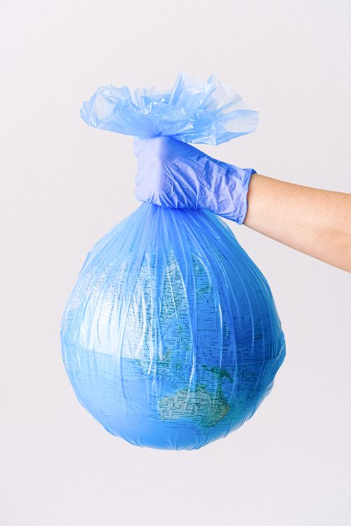 Free A globe encased in a blue plastic bag held by a gloved hand, representing environmental issues. Stock Photo