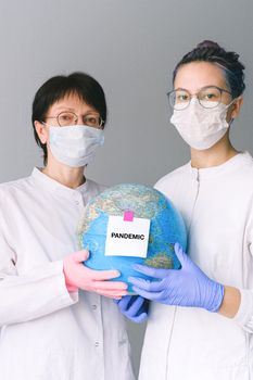 两名医护人员举着一个象征全球健康危机的“流行病”地球仪