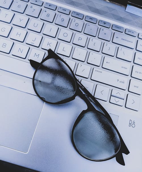 Black Framed Sunglasses on Gray Laptop Keyboard