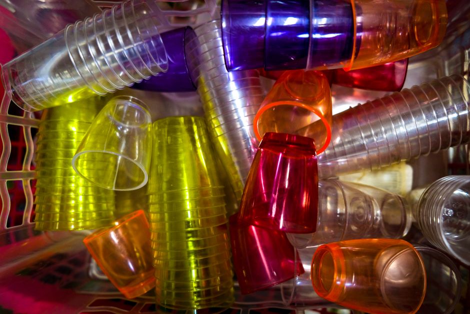 Rows of red, orange, and blue jello shots in small plastic cups, some pushed up from the bottom to show the firm set.