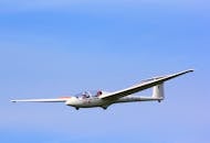 在晴朗的蓝天背景下，一架双座滑翔机优雅地飞行