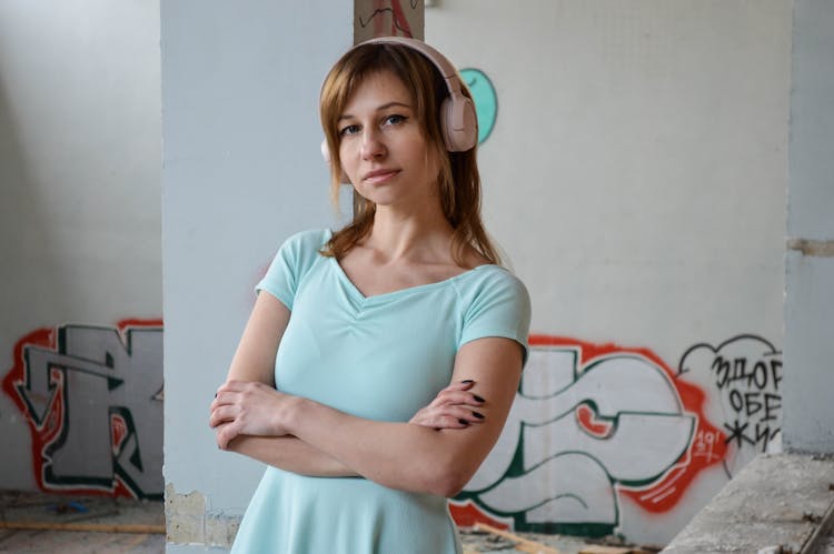 Woman Listening To Music In Headset Near Wall With Graffiti