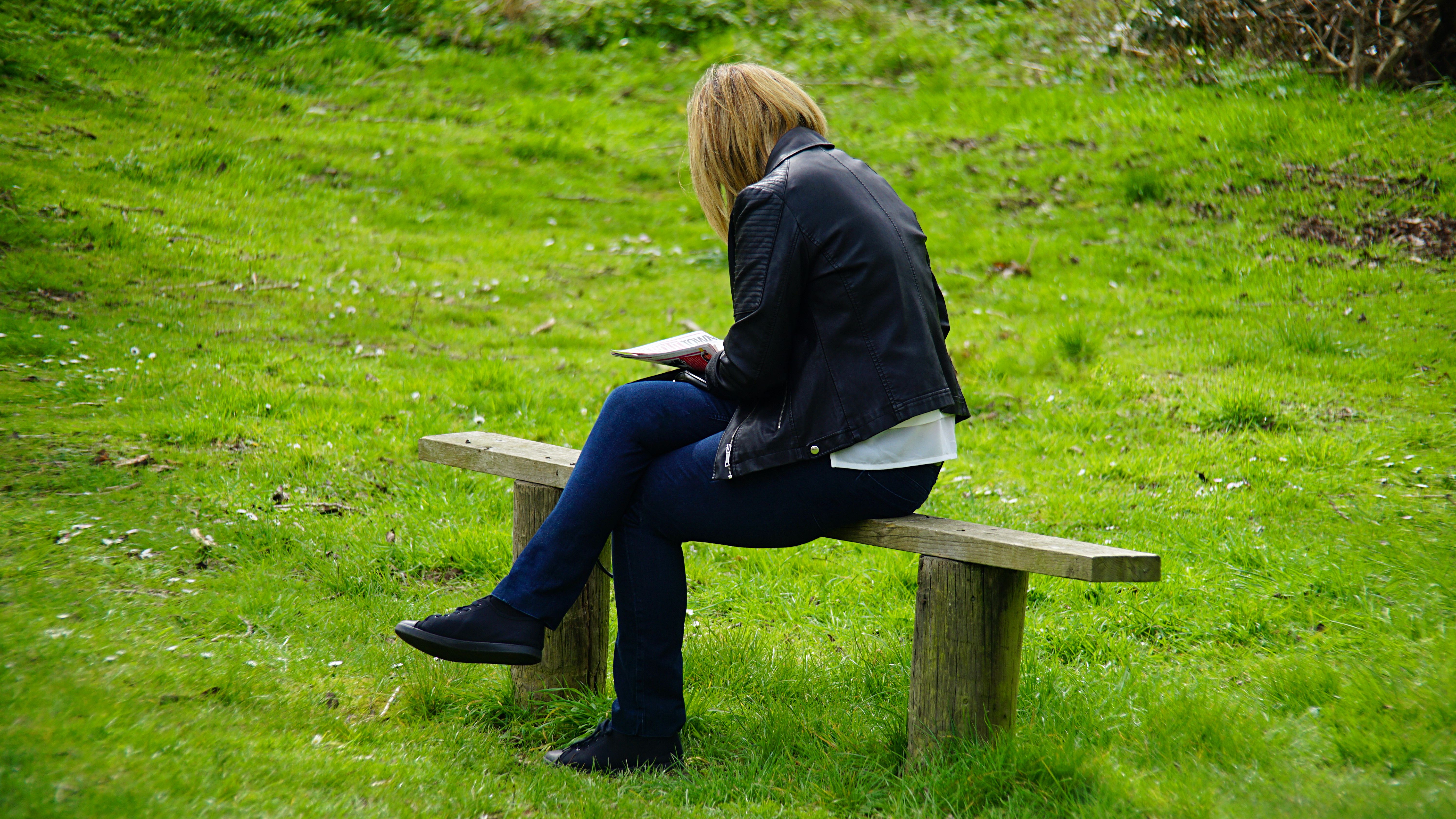 person sitting on a park bench reading a book, calm atmosphere