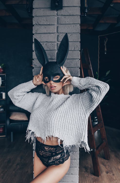 Woman in Gray Sweater Wearing Black and White Rabbit Mask