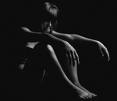 Grayscale Photo of a Woman Sitting on the Floor