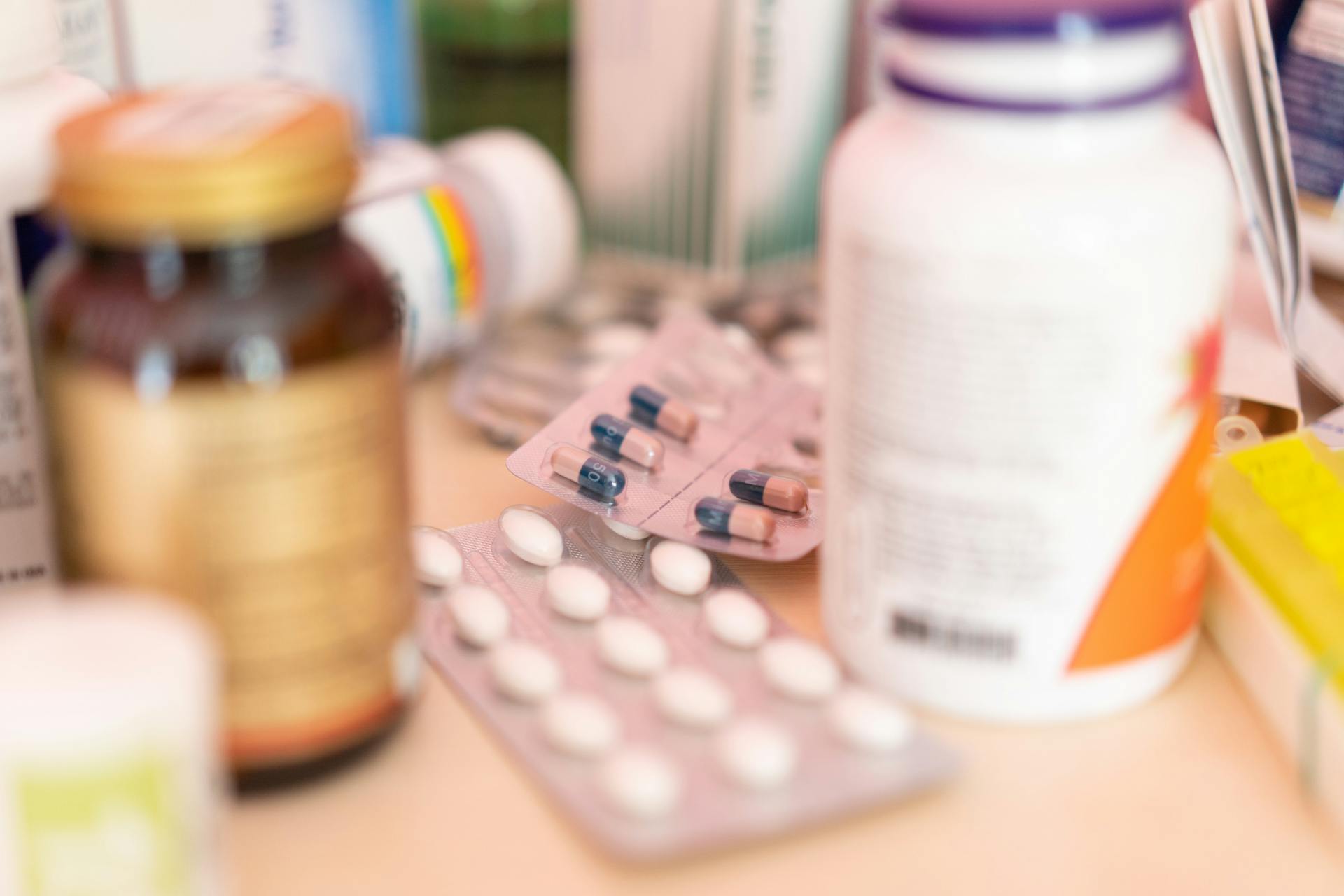 Close-up shot of various pharmaceutical pills, capsules, and medication bottles on a table.