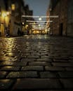 夜晚，节日的灯光和潮湿的倒影照亮了鹅卵石街道