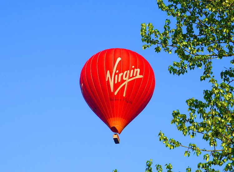 Red Hot Air Balloon Flying Against Blue Sky