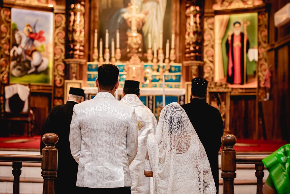 A bride and groom during a traditional wedding ceremony in a beautifully decorated church interior.
