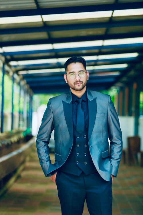 Free Businessman in sleek gray suit posing confidently in outdoor corridor. Stock Photo