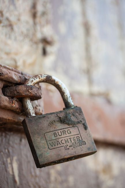 Fotomural Primer plano de un candado oxidado en una puerta de madera desgastada, enfatizando la seguridad.