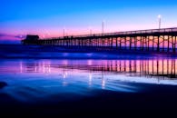 黄昏时分，码头的明亮灯光倒映在大海上，营造出宁静的海景