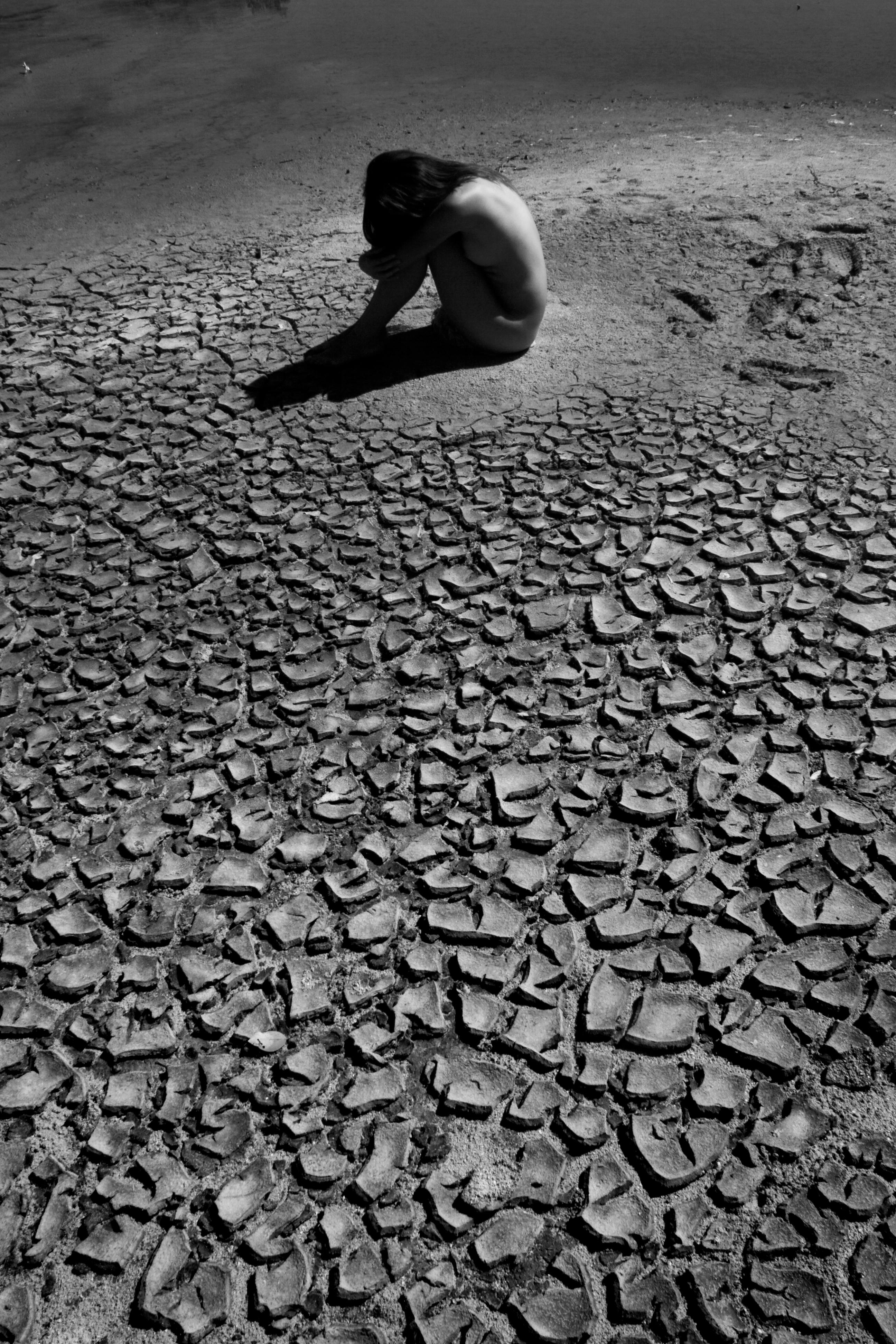 naked woman sitting on a dry land