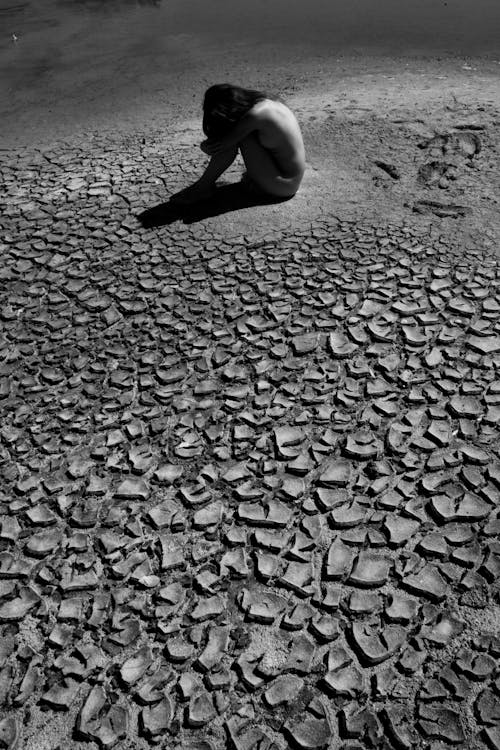 Naked Woman Sitting on a Dry Land 