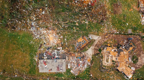 Aerial view of dramatic consequences of massive hurricane with ruined houses and kindling woods lying on green lawn
