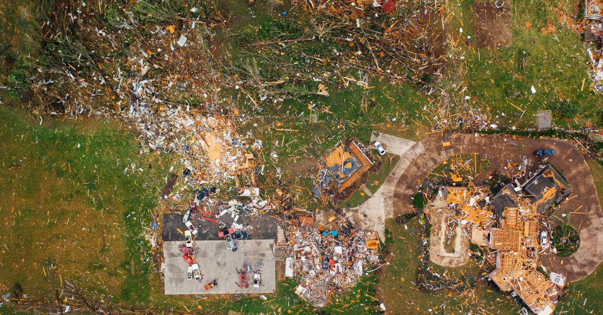Aerial view of dramatic consequences of massive hurricane with ruined houses and kindling woods lying on green lawn