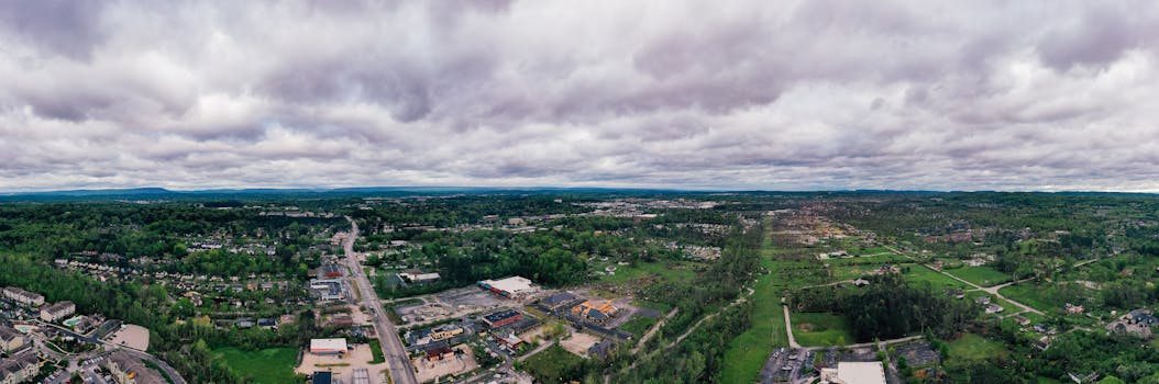 Panoramic aerial view showcasing suburban Chattanooga, TN with lush greenery and residential areas under a cloudy sky.