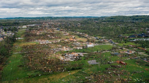 Aerial view aftereffects of massive storm on small village including windthrown bent trees and destroyed buildings