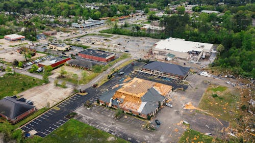 Aerial view of terrible consequences of thunderstorm on small town buildings with ruined roof and uprooted trees