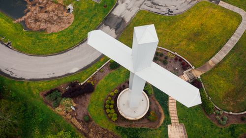 Free Aerial view of contemporary large white crucifix located on peaceful green valley in countryside Stock Photo
