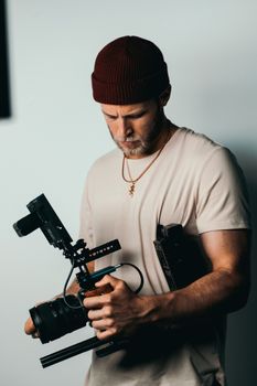 Portrait of a bearded videographer adjusting professional camera equipment indoors.