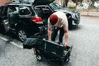 Man in Gray T-shirt and Gray Shorts Holding Black Stroller Near Black Suv