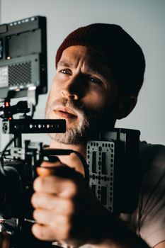 Portrait of a focused videographer with camera indoors.