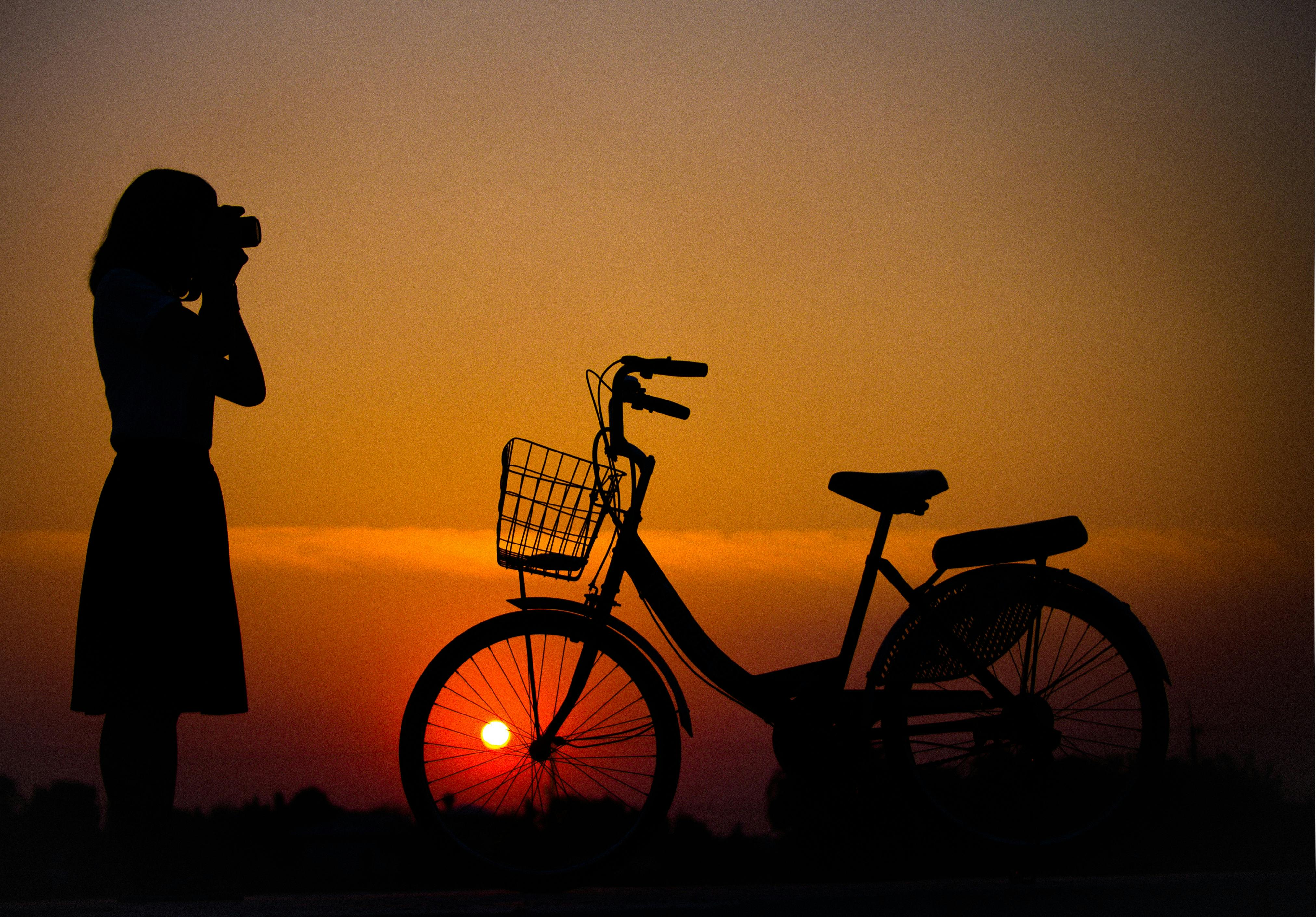 Silhouette of Woman Using Camera in Front of City Bicycle · Free Stock Photo