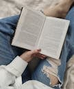Crop faceless woman reading book on bed